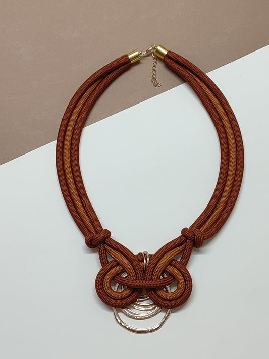 Colar de cordão grosso modelo Nodum com cordão castanho e castanho-madeira e detalhe assimétrico de nós em espiral contínua texturada num dos lados e pendente geométrico na base.