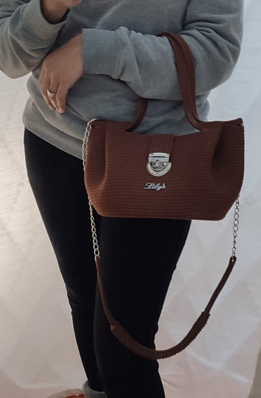 Mulher usando Bolsa artesanal Cordame Chic em cordão de algodão castanho com alça de ombro removível e ferragens metálicas.