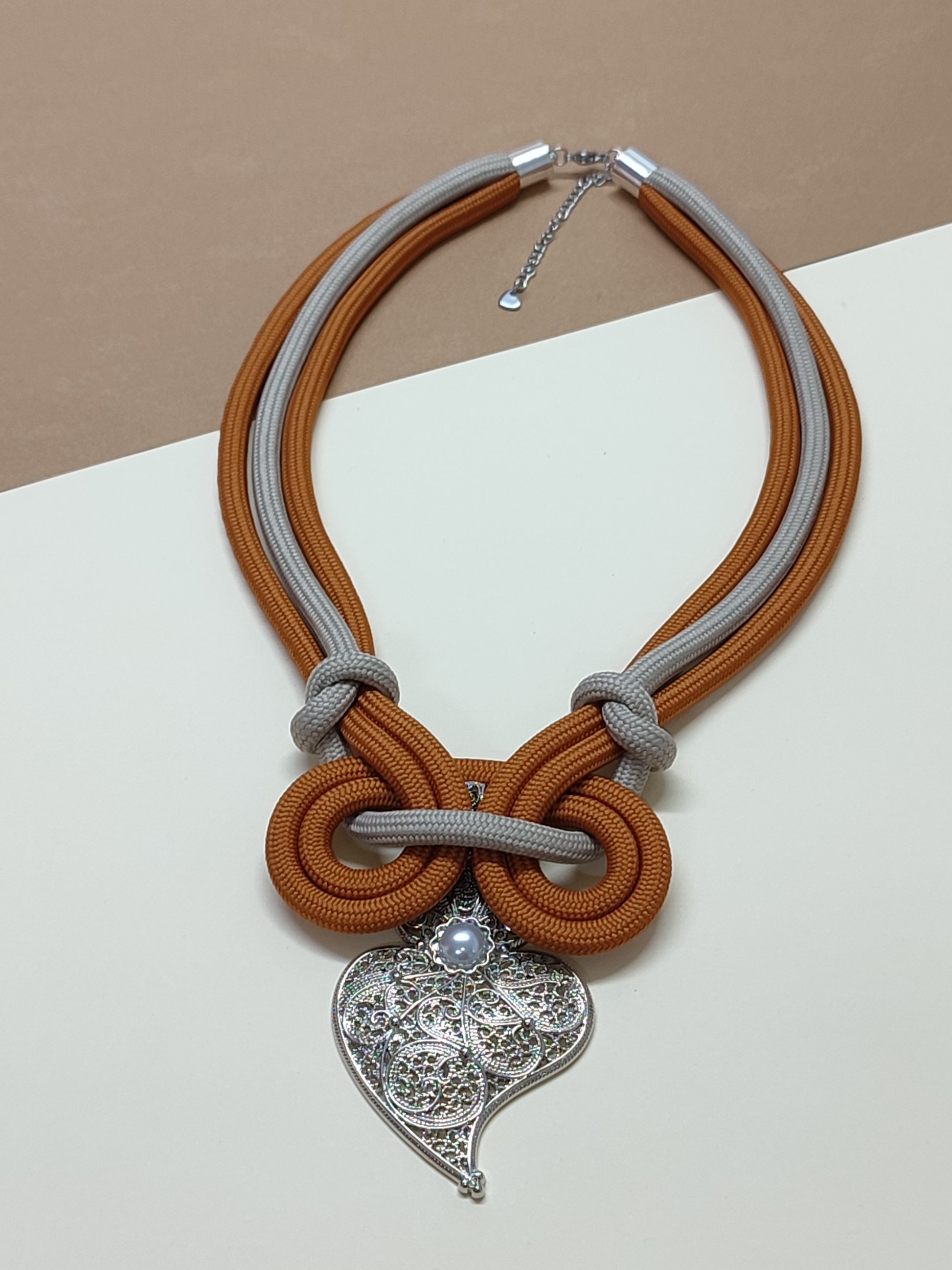 Colar de cordão artesanal modelo Laço com design simétrico de nós em espiral contínua e pendente ornamental de destaque na base