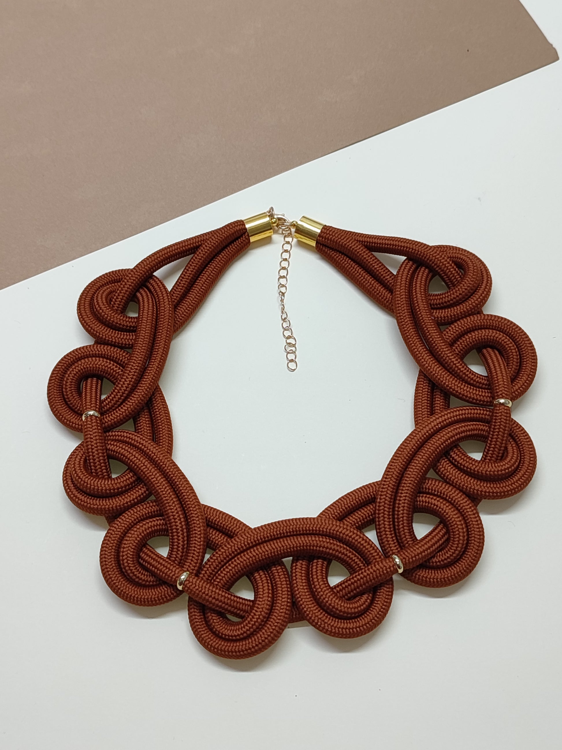 Maxicolar estilo gola artesanal modelo Imperial em cor castanho com padrão contínuo de laços em espiral estruturados que cobrem todo o decote.