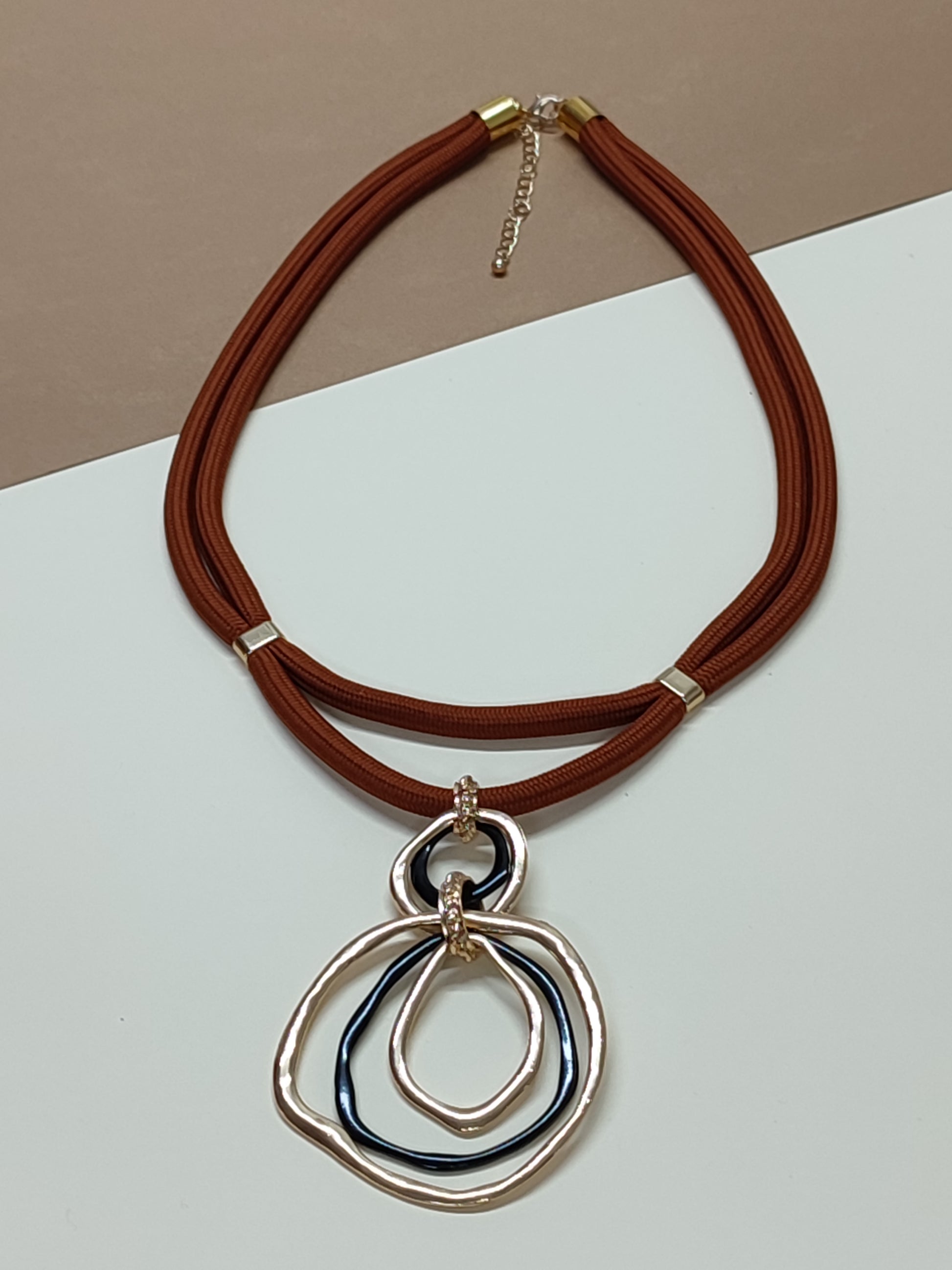 Colar artesanal modelo Dualis com estrutura de cordão duplo paralelo em cor castanho e pendente ornamental de destaque na base.