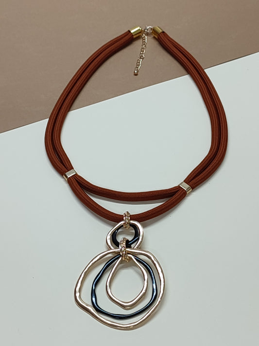 Colar artesanal modelo Dualis com estrutura de cordão duplo paralelo em cor castanho e pendente ornamental de destaque na base.