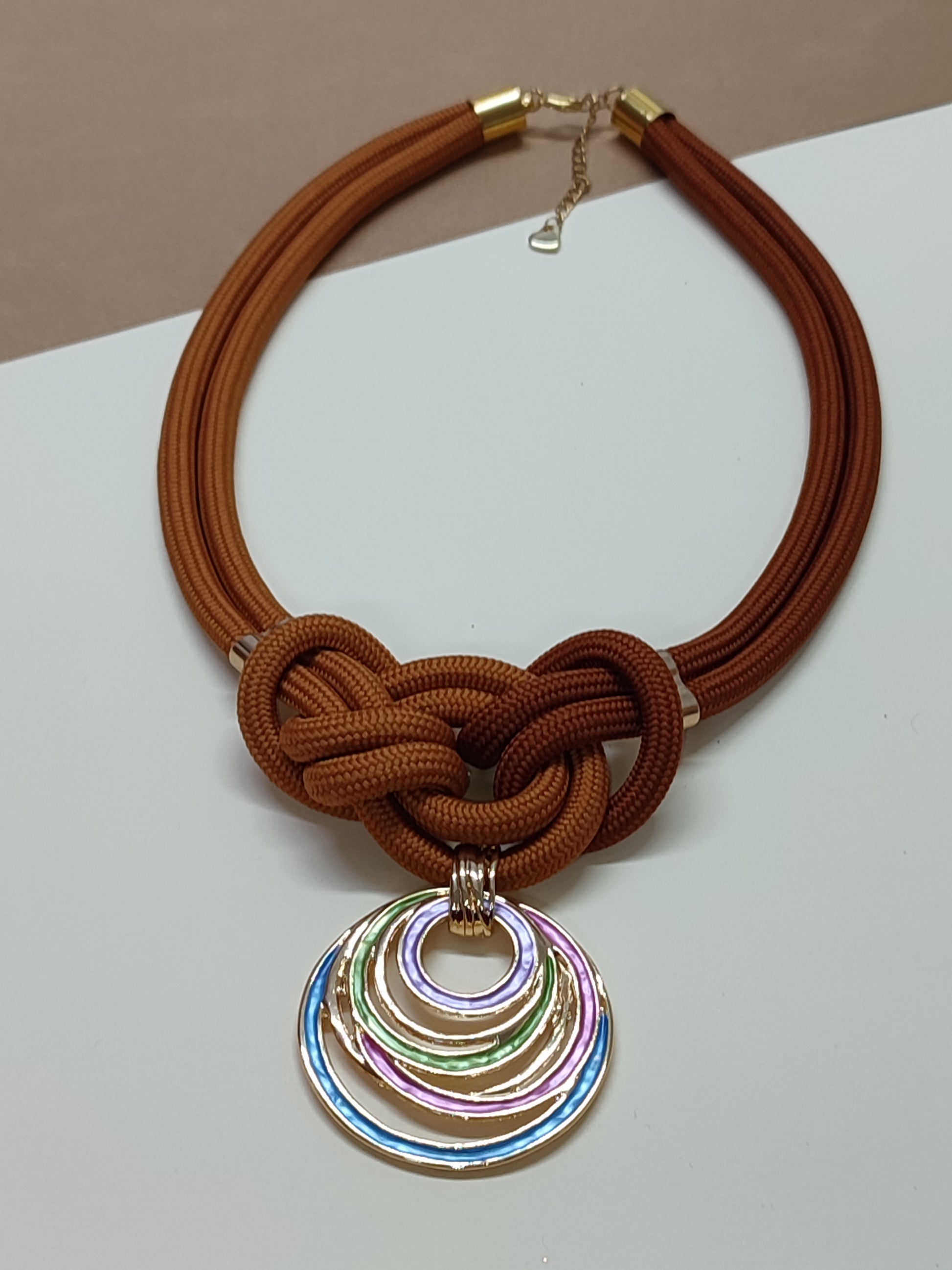 Colar artesanal modelo Marina com estrutura de cordão duplo e nudo marinheiro central simétrico com pendente decorativo na base.
