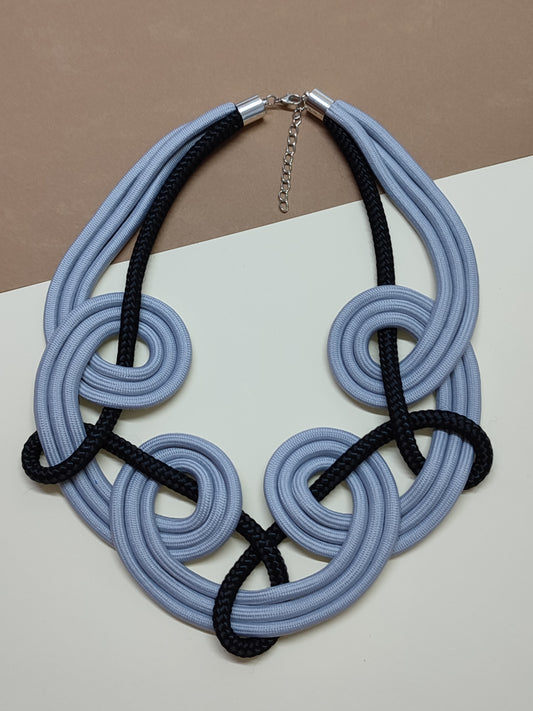 Maxicolar artesanal modelo Nexus com design arquitetónico de cordões múltiplos em espirais concêntricas e trançado de contraste geométrico.