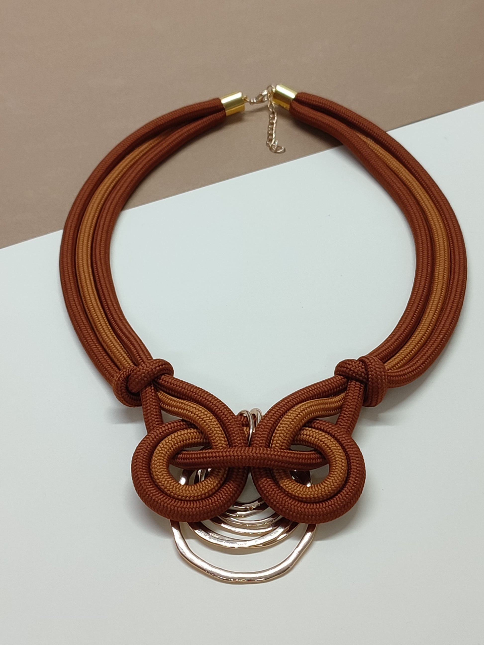 Colar de cordão grosso modelo Nodum com detalhe assimétrico de nós em espiral contínua texturada num dos lados e pendente geométrico na base.